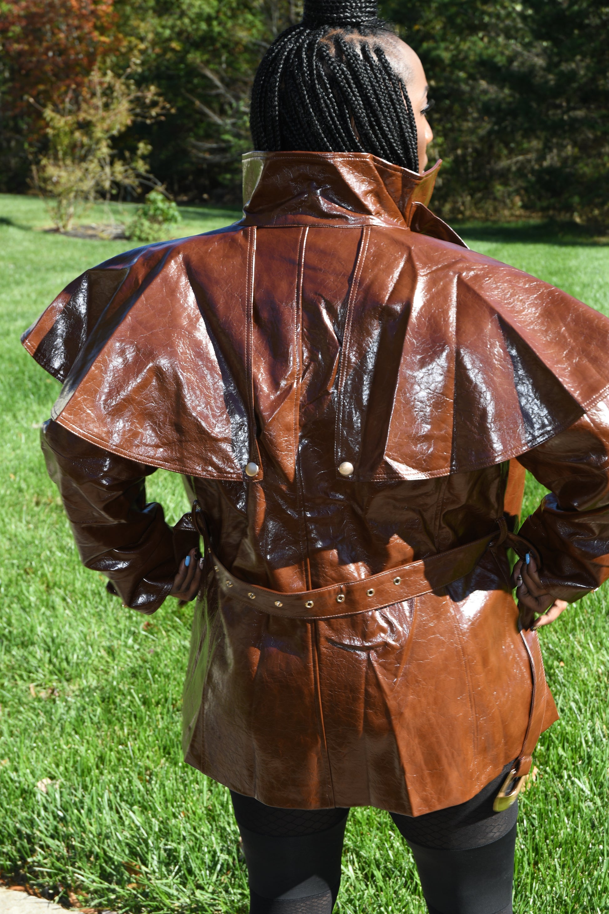 Brown leather coat with a hood worn by a person on grass