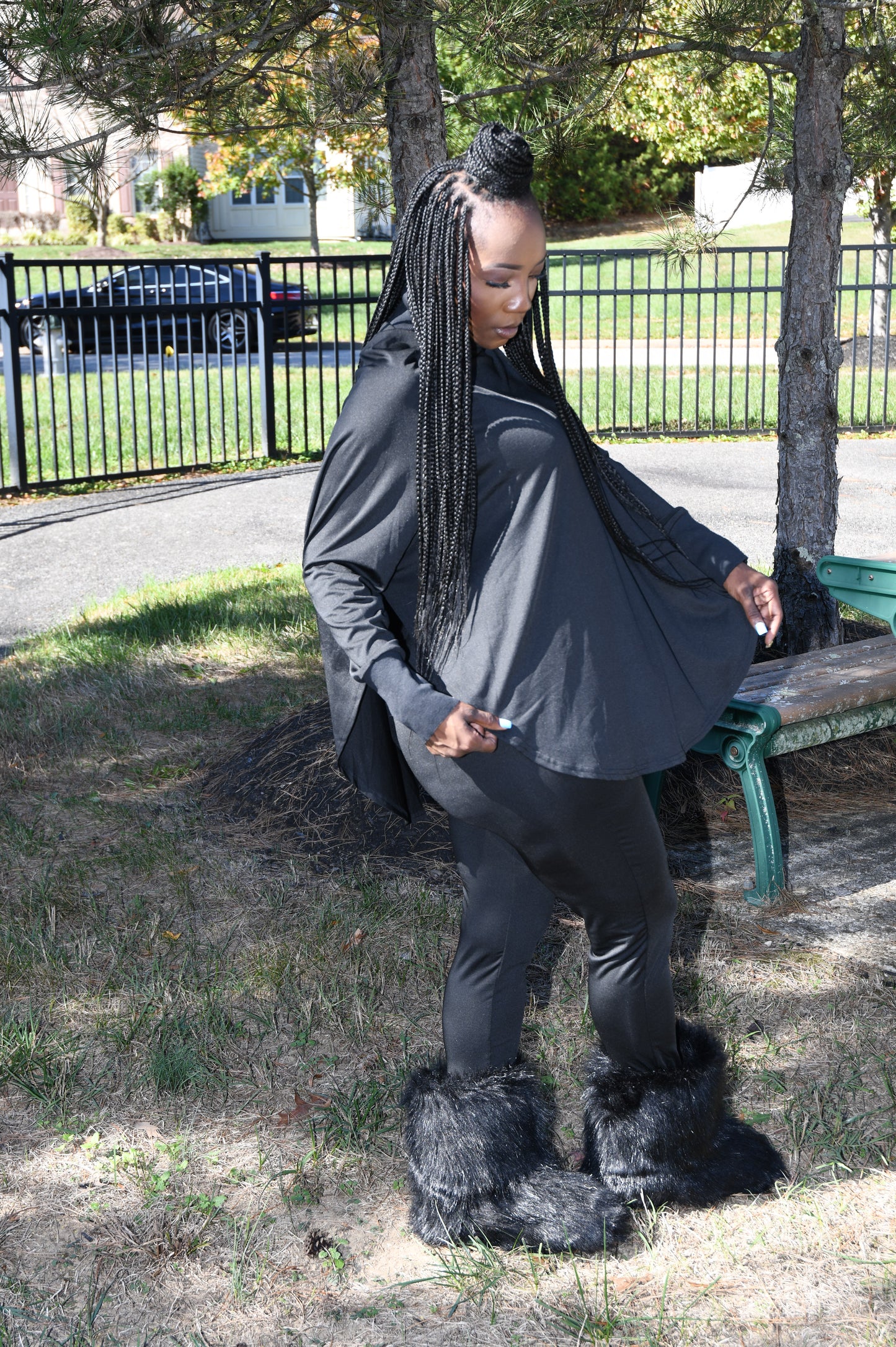 Person wearing a black coat with fur-lined hood in an outdoor setting