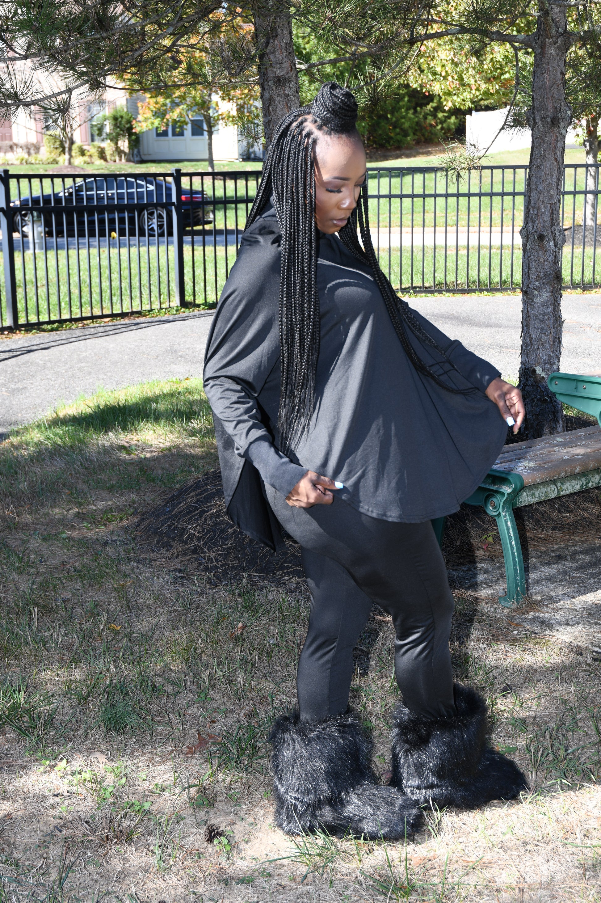 Person wearing a black coat with fur-lined hood in an outdoor setting